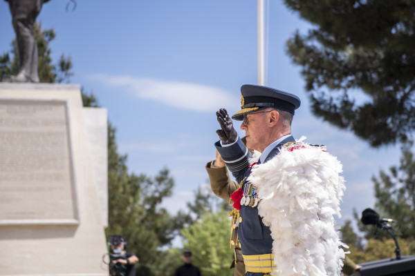 A man in highly decorated Air Force uniform saluting a memorial