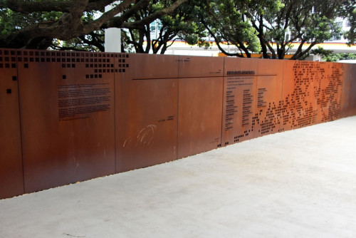 A tarnished, flat metal memorial with cut out text
